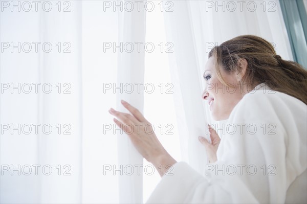 Woman wearing bathrobe looking through window.
Photo : Jamie Grill