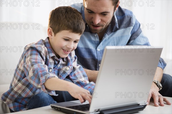 Father working on laptop with his son (8-9) .
Photo : Jamie Grill