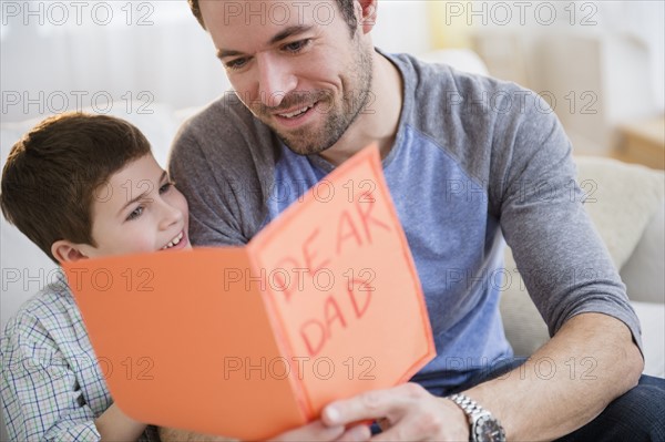 Father and son (8-9) looking at greeting card.
Photo : Jamie Grill