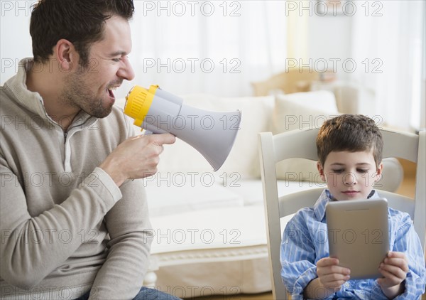Father yelling into megaphone to discipline son (8-9).
Photo : Jamie Grill