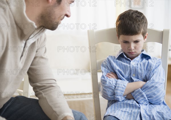 Father looking at displeased son (8-9) .
Photo : Jamie Grill