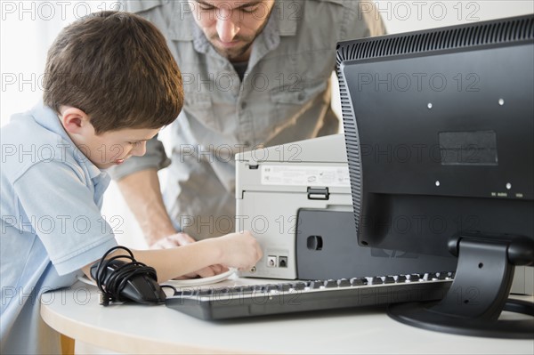 Father and son (8-9) setting up printer with computer on table.
Photo : Jamie Grill