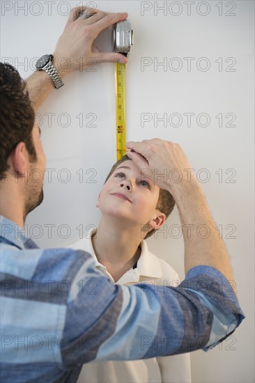 Father measuring height of son (8-9) .
Photo : Jamie Grill