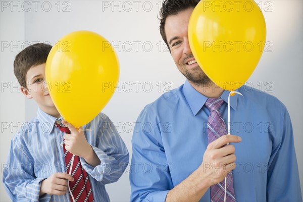 Father and son (8-9) peeking behind yellow balloons.
Photo : Jamie Grill
