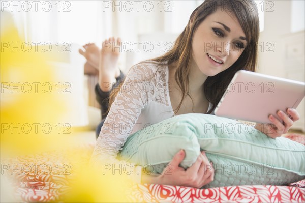 Young woman lying on bed with digital tablet.
Photo : Jamie Grill