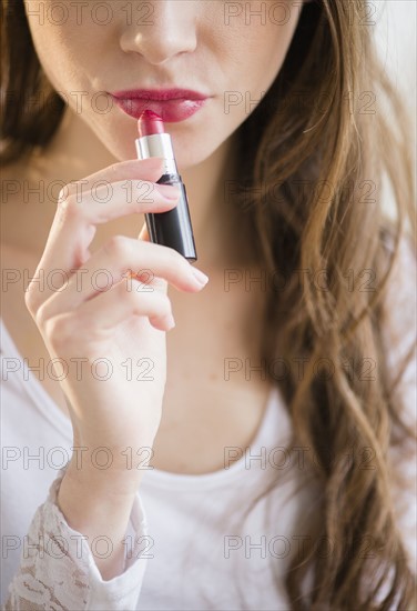 Young woman applying lipstick.
Photo : Jamie Grill