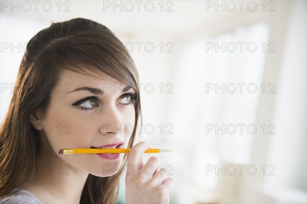 Young woman holding pencil in her mouth.
Photo : Jamie Grill