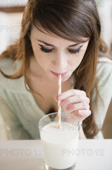 Young woman drinking milk with straw.
Photo : Jamie Grill