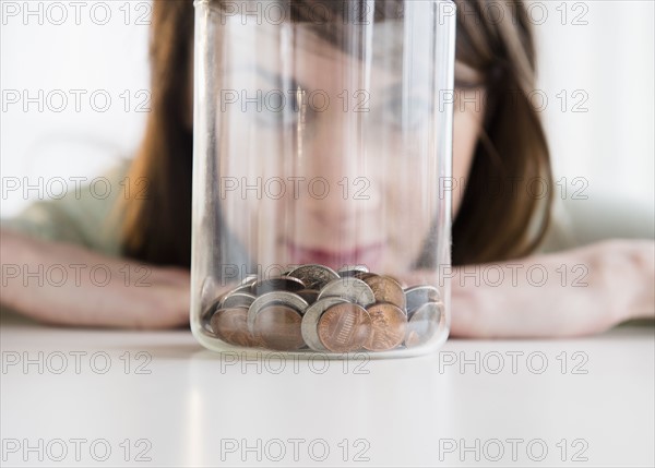 Young woman looking at coins in jar.
Photo : Jamie Grill