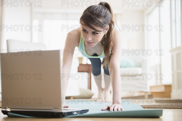 Young woman using laptop during exercising.
Photo : Jamie Grill