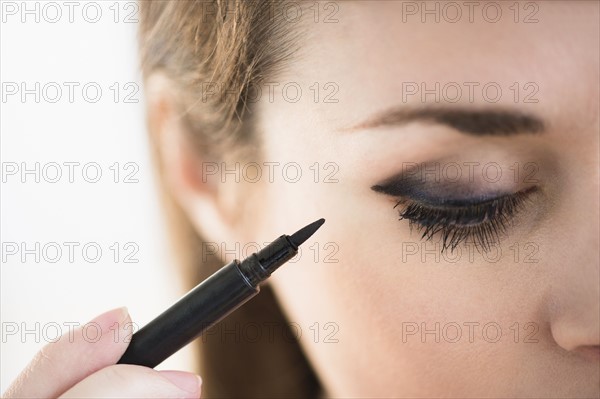 Young woman applying eyeliner.
Photo : Jamie Grill