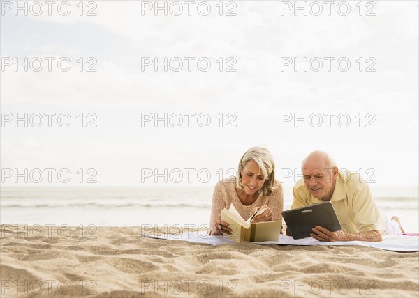 Senior couple reading books on beach.
Photo : Daniel Grill