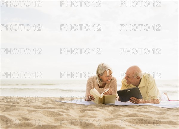 Senior couple reading books on beach.
Photo : Daniel Grill