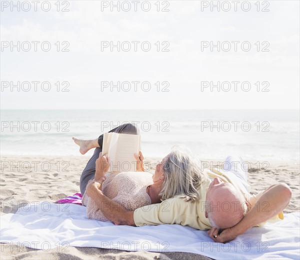 Senior couple reading books on beach.
Photo : Daniel Grill