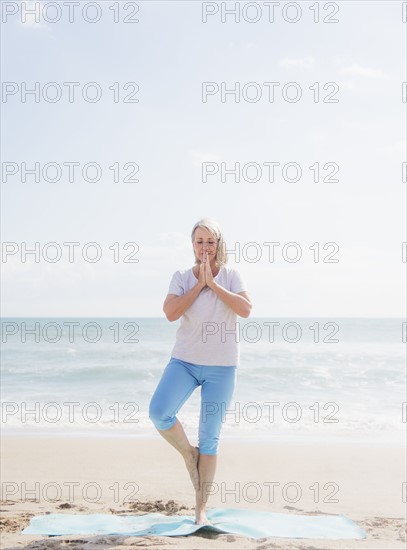 Senior woman practicing yoga on beach.
Photo : Daniel Grill