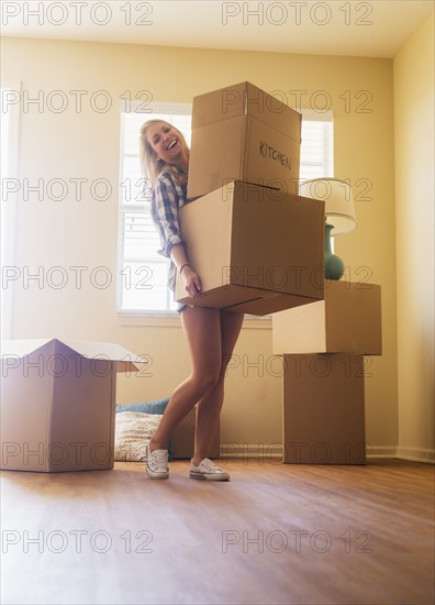 Young woman carrying boxes in her new house.
Photo : Daniel Grill