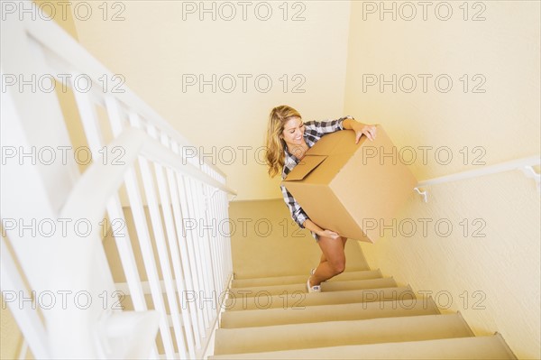 Young woman carrying box in her new house.
Photo : Daniel Grill