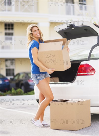 Young woman carrying box from car into her new house.
Photo : Daniel Grill