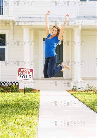 Woman jumping in front of new house.
Photo : Daniel Grill