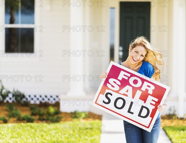 Woman holding for sale sign.
Photo : Daniel Grill