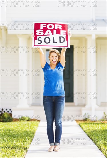 Woman holding for sale sign.
Photo : Daniel Grill