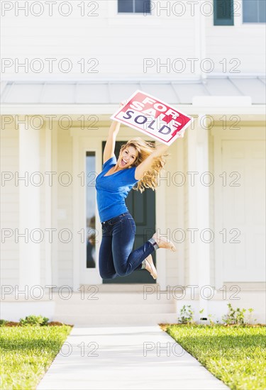 Woman jumping in front of new house.
Photo : Daniel Grill