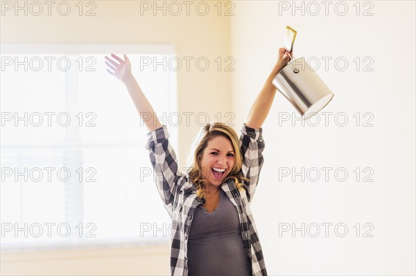 Happy woman holding paint bucket.
Photo : Daniel Grill