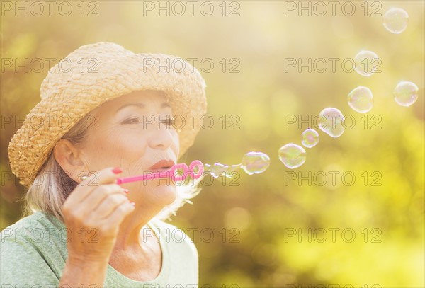 Senior woman blowing soap bubbles.
Photo : Daniel Grill