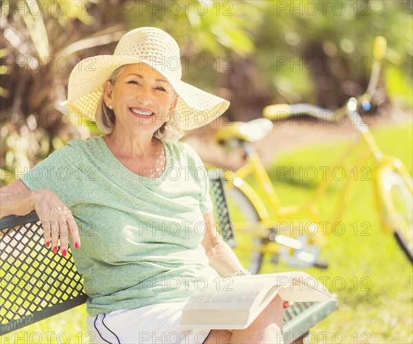 Portrait of senior woman reading book in park.
Photo : Daniel Grill