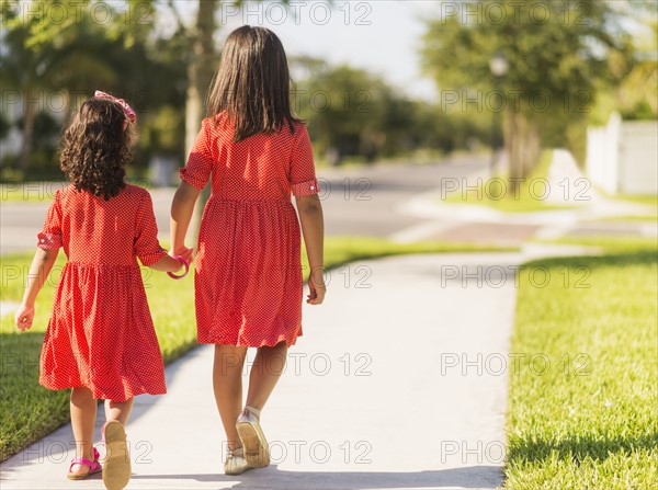 Back view of girls( 4-5, 8-9) holding hands.
Photo : Daniel Grill