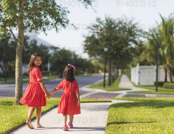 Back view of girls( 4-5, 8-9) holding hands.
Photo : Daniel Grill