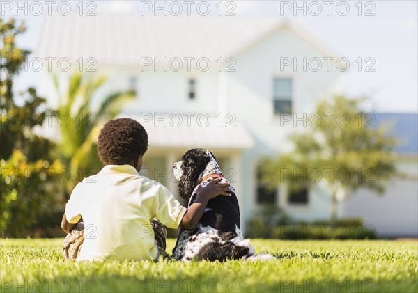 Back view of boy (6-7) sitting with dog.
Photo : Daniel Grill