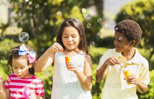 Girls( 4-5, 8-9) and boy (6-7) blowing soap bubble.
Photo : Daniel Grill