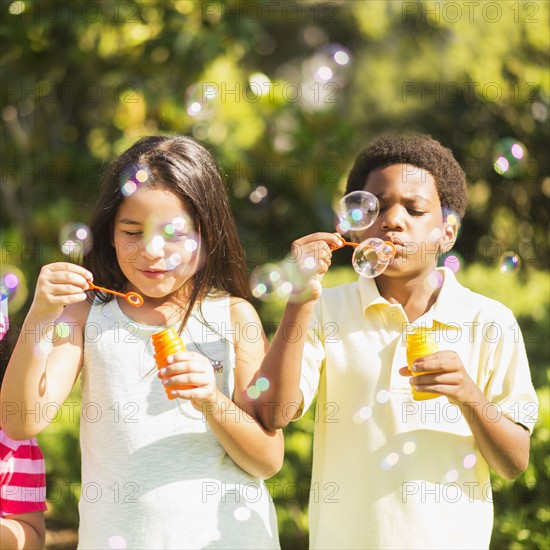 Girls( 4-5, 8-9) and boy (6-7) blowing soap bubble.
Photo : Daniel Grill