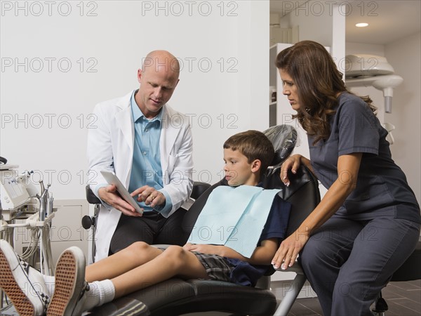 Dentist holding digital tablet with patient's( 12-13) x-ray.