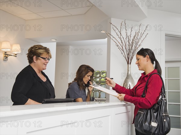 Female patient at doctor's office front desk.