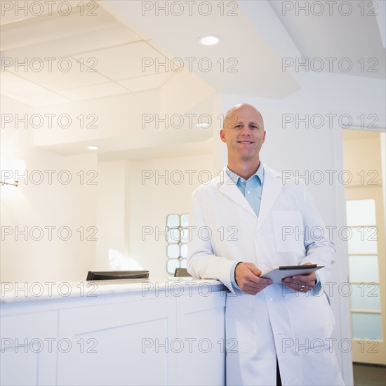 Doctor leaning against reception desk.