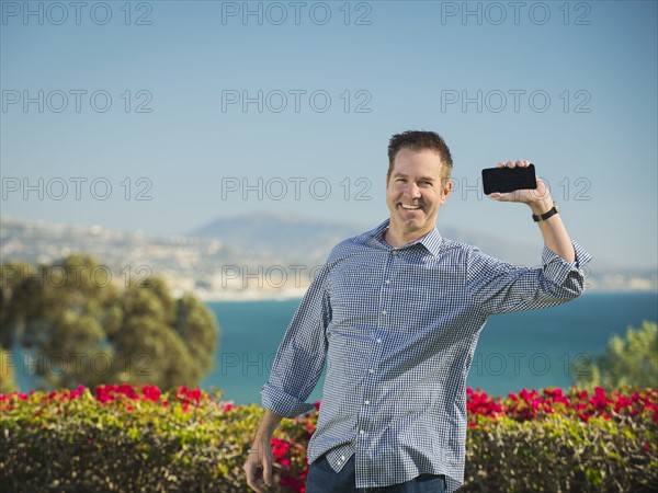 Portrait of smiling man holding smartphone.