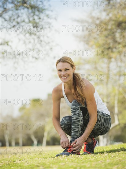 Woman in park tying shoe.