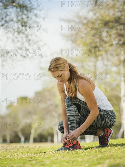 Woman in park tying shoe.