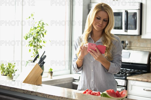 Woman text messaging in kitchen.
Photo : pauline st.denis