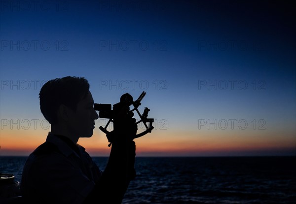 Man looking through sextant.