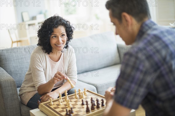 Couple playing chess in living room.