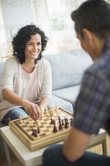 Couple playing chess in living room.