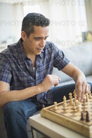 Man playing chess in living room.