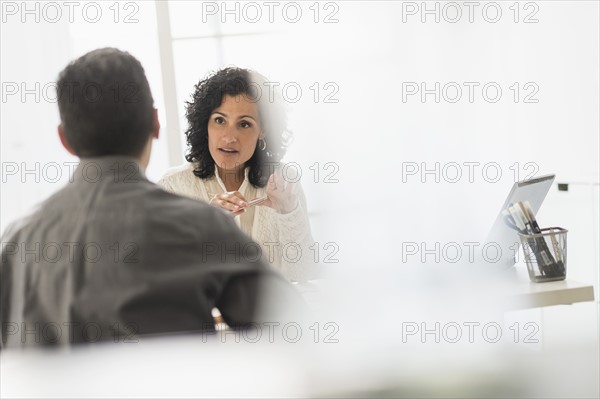 Business people talking at desk in office.