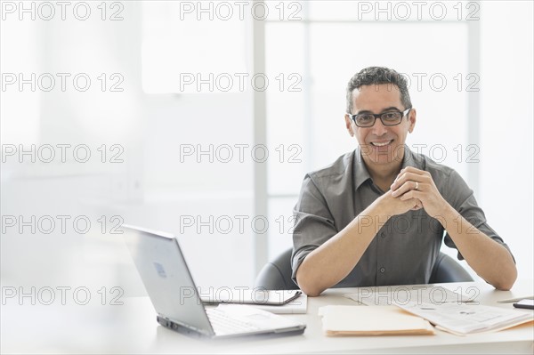 Portrait of man at desk in office.