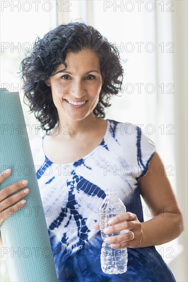 Portrait of smiling woman with yoga mat.