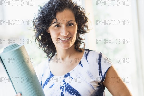 Portrait of smiling woman with yoga mat.