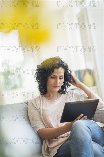 Woman using digital tablet on sofa.